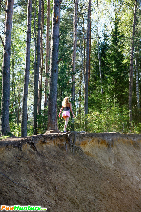 Muñeca joven lujuriosa se desnuda y orina en un tranquilo claro del bosque
 #78690878