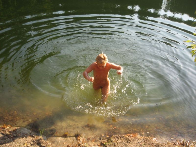 Nudista bruna tira su un po' d'acqua in una spiaggia nudista
 #72248492