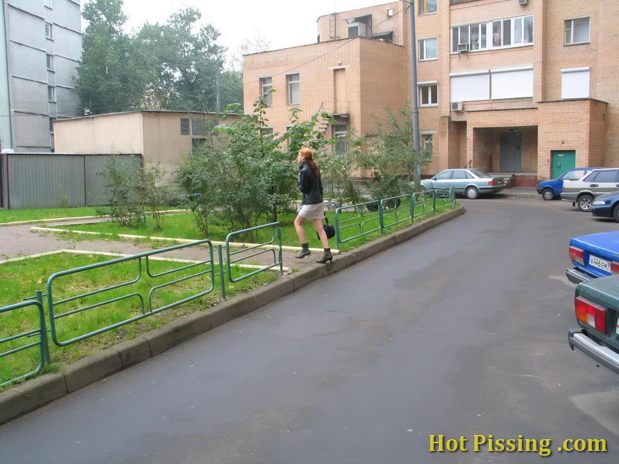 Hidden camera photos of a redhead girl having a pee behind a building
