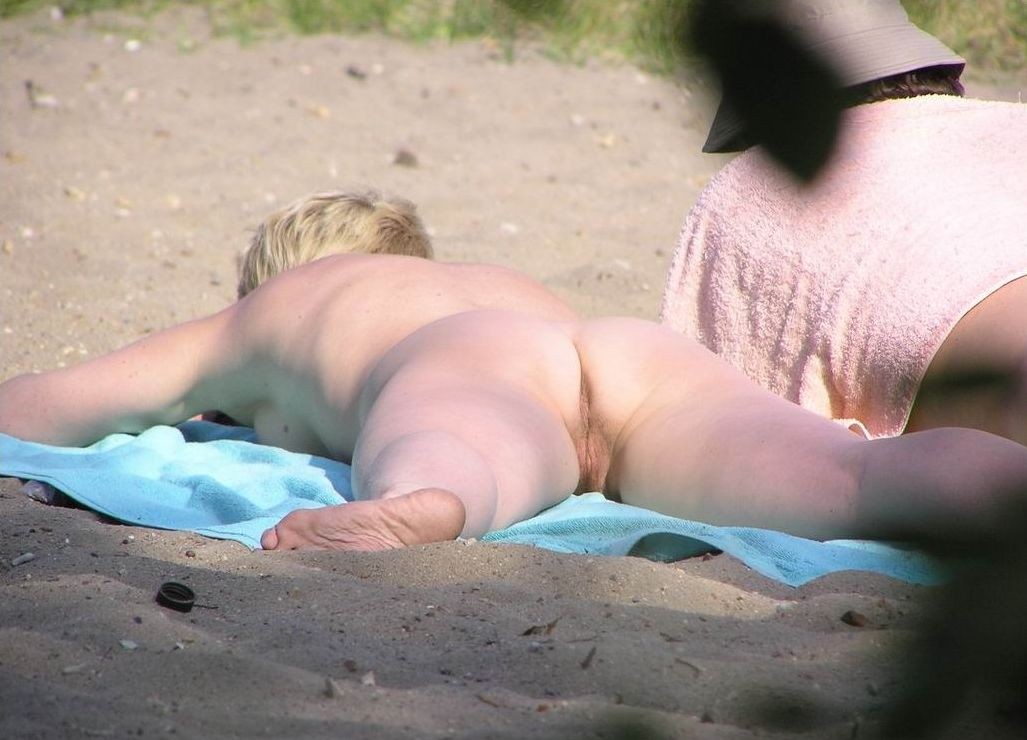 Blonde nudist kicks up some water at a nude beach #72255411