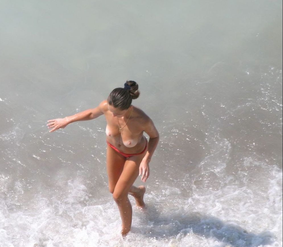 Nudista bionda tira su un po' d'acqua in una spiaggia nudista
 #72255442
