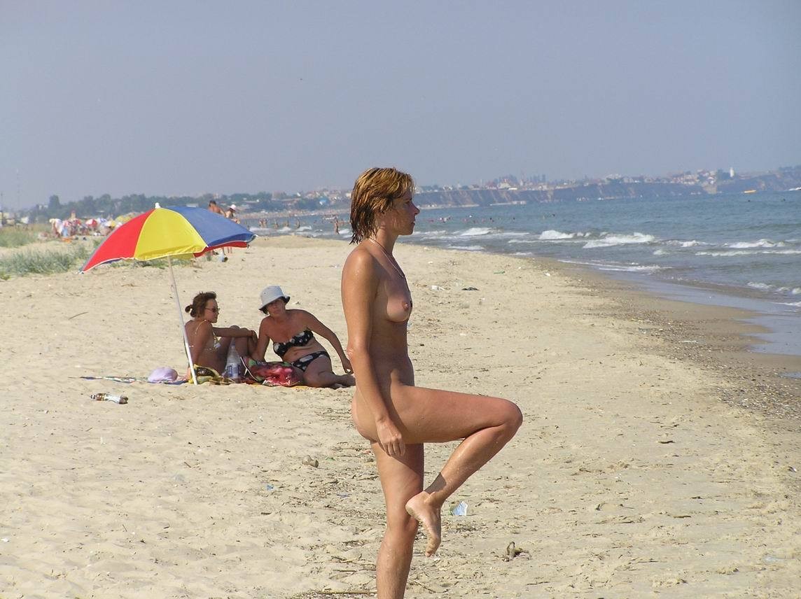 Perky breasted nude female poses on a nude beach front #72250008