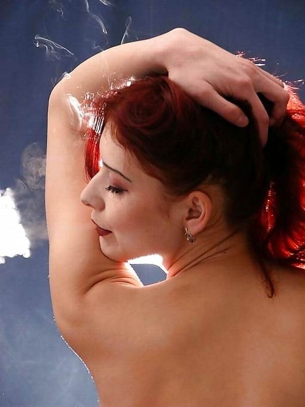 Rotschopf Mädel raucht eine Zigarette, während sie posiert
 #67861269