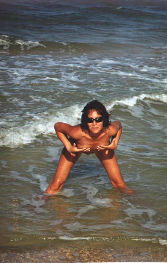 Une jeune femme bien roulée se dénude au soleil sur une plage nudiste. #72252122