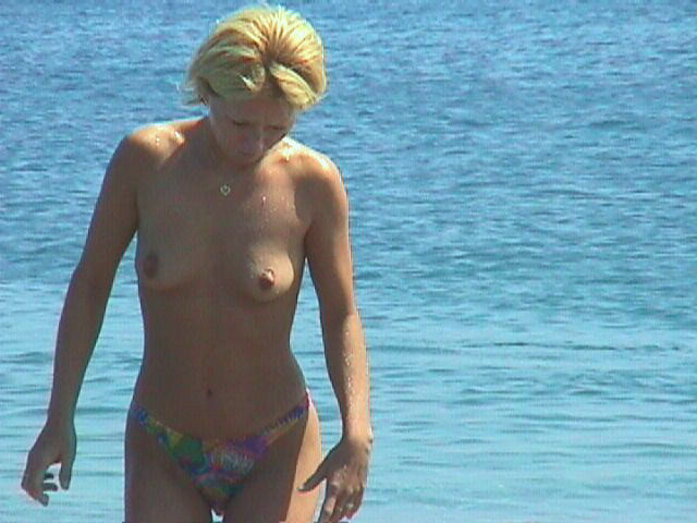Une jeune femme bien roulée se dénude au soleil sur une plage nudiste. #72252223