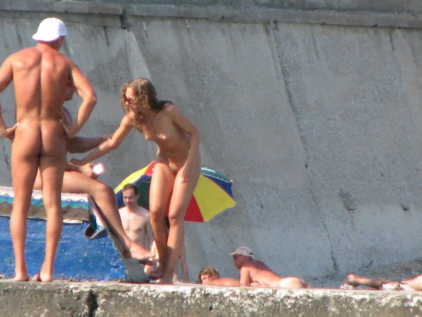 Une jeune nudiste brune se déshabille pour faire bronzer son corps nu.
 #72256752