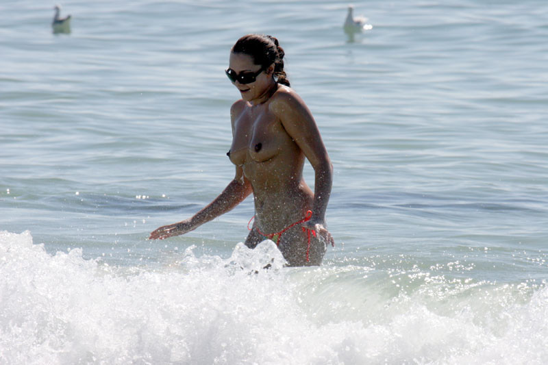 Une jeune nudiste montre son corps mince à la plage.
 #72256733