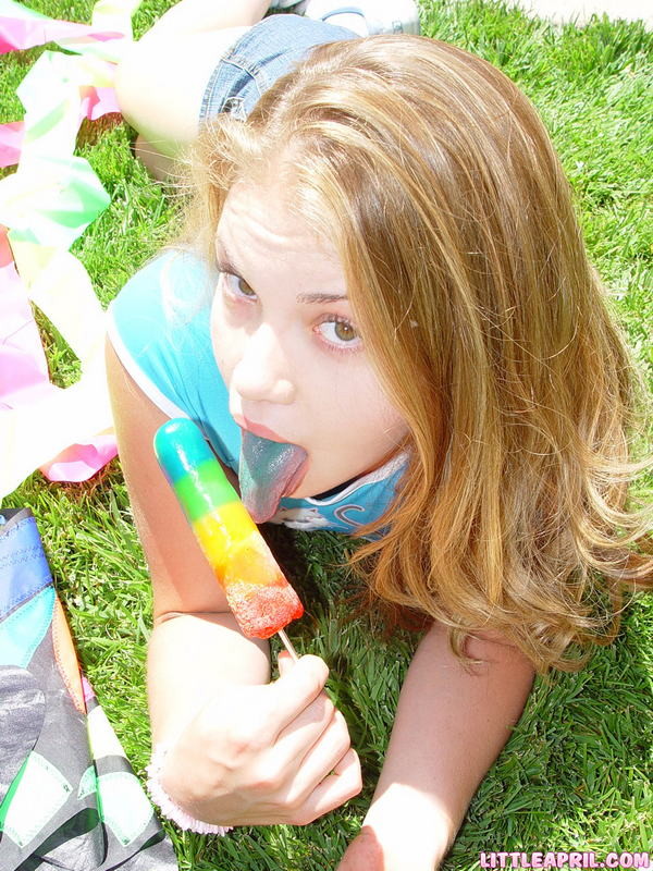 Une jeune fille de 18 ans suce et joue avec une glace fondante en plein air.
 #78603863