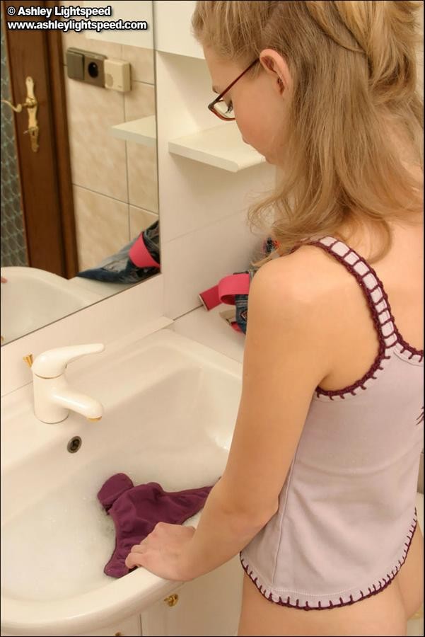 Junges blondes Teenie wäscht ihr schmutziges Höschen in einem Waschbecken
 #78679575