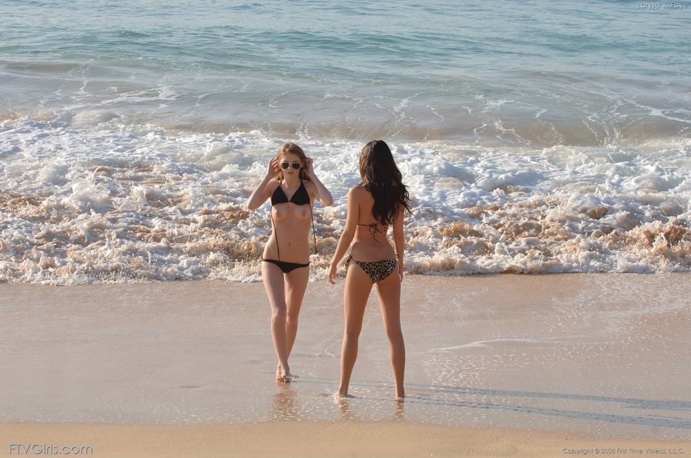 Deux jeunes filles en bikini sexy exhibant leurs seins sur une plage de sable.
 #72315574