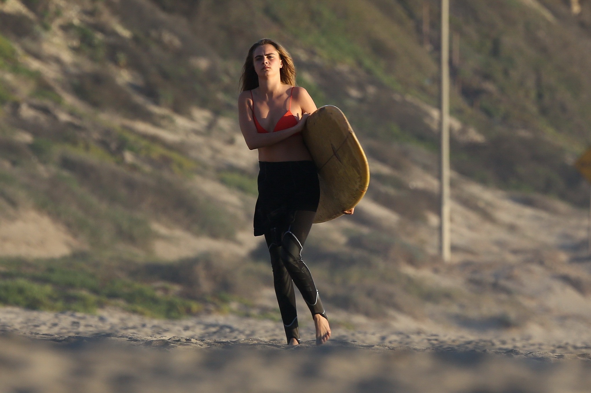 Cara Delevingne wearing red bikini top and black wetsuit while filming Paper Tow #75175683