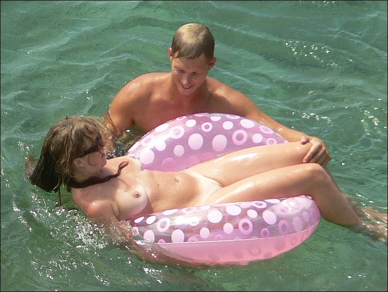 Una chica desnuda se lo pasa en grande bajo el sol de la playa
 #72259510