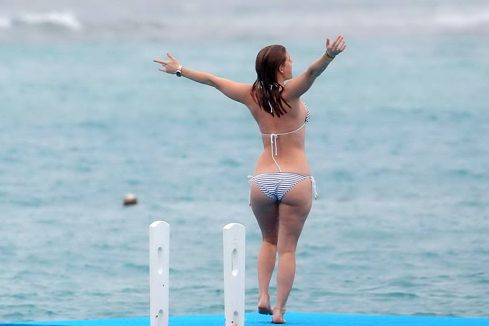 Alice eve en train de se glisser hors de son bikini à rayures sur une plage de la Barbade. #75208957
