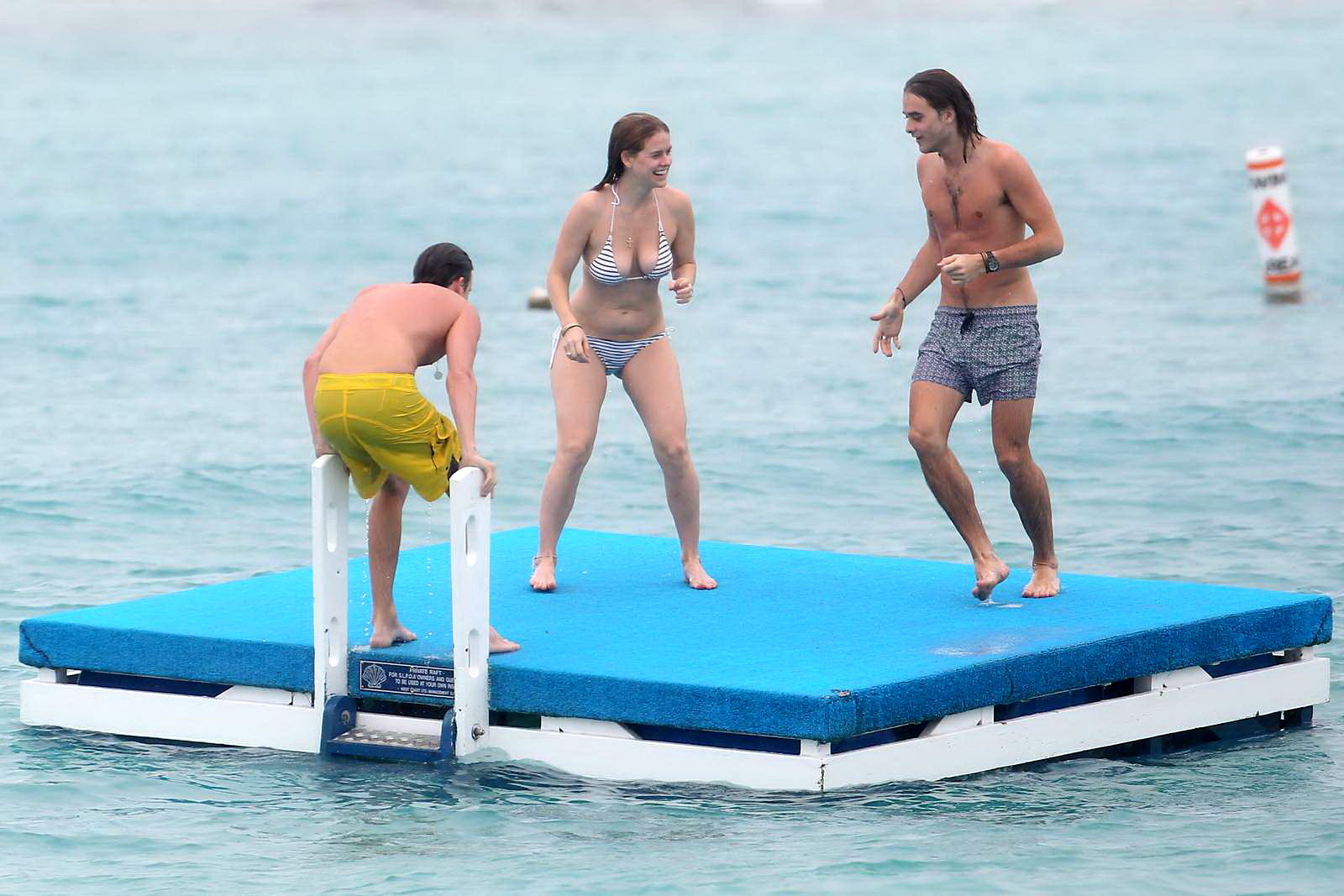 Alice eve en train de se glisser hors de son bikini à rayures sur une plage de la Barbade. #75208965