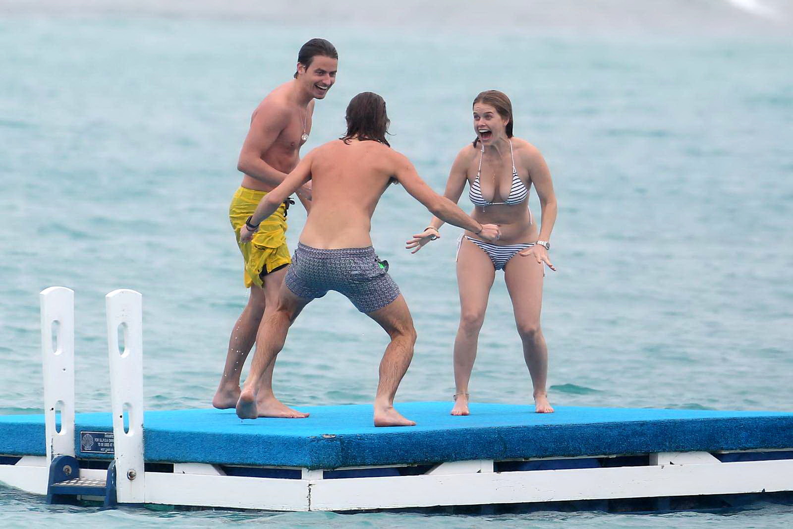 Alice eve en train de se glisser hors de son bikini à rayures sur une plage de la Barbade. #75208982