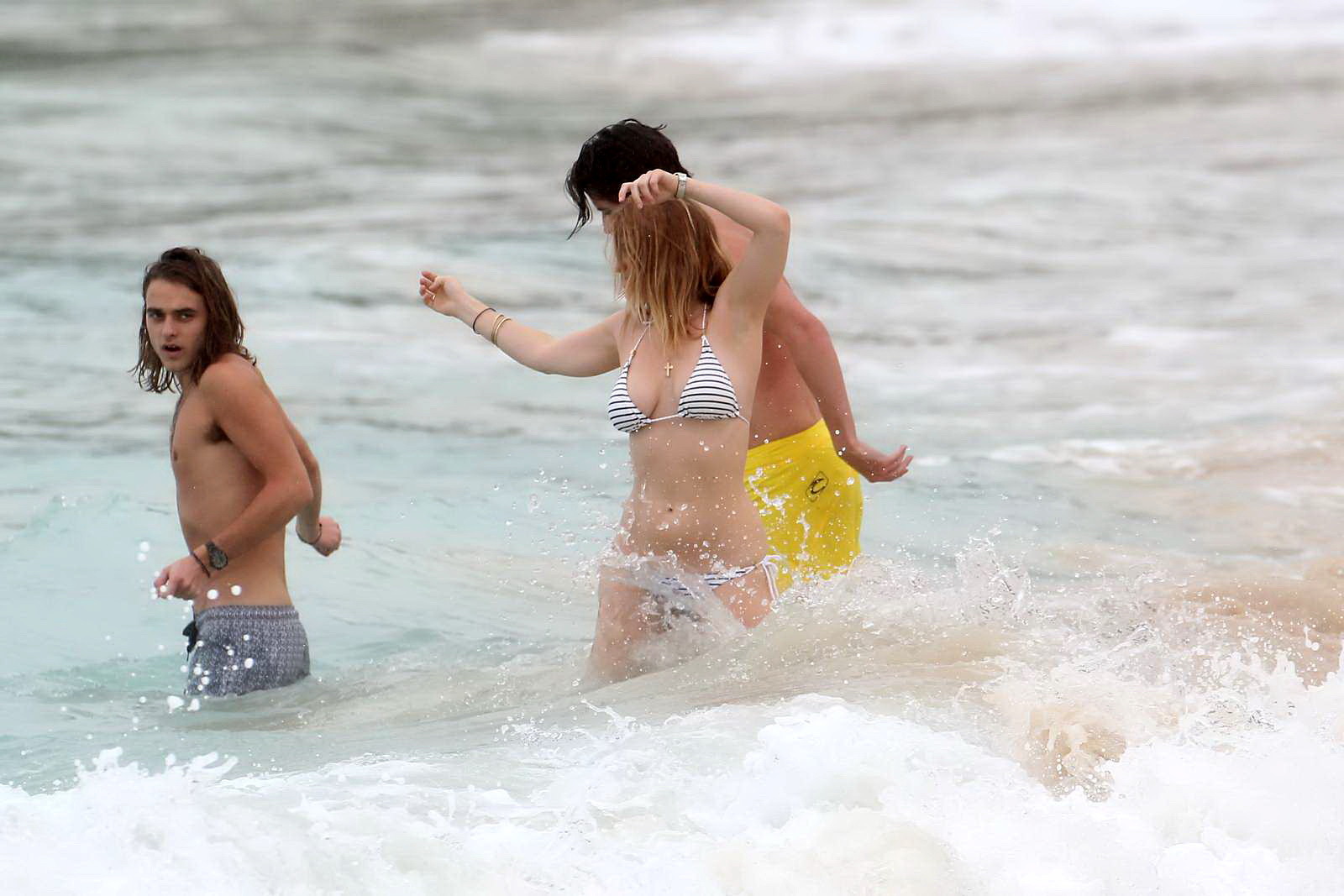 Alice eve en train de se glisser hors de son bikini à rayures sur une plage de la Barbade. #75209061