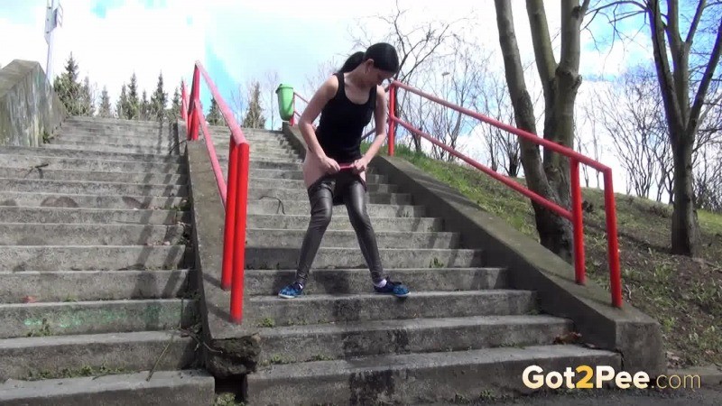 Chica de pelo oscuro orina en los escalones de hormigón
 #67499763