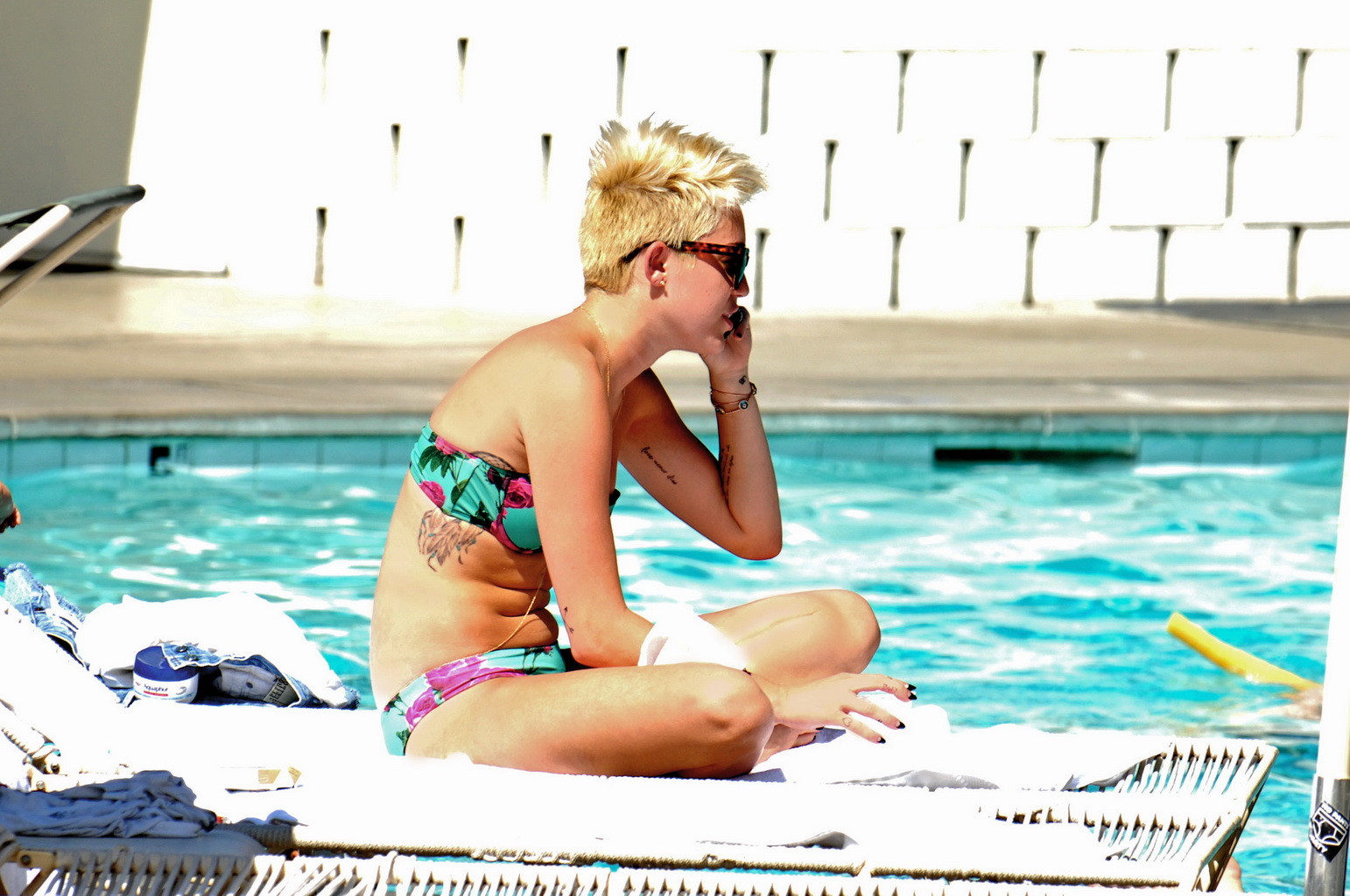 Miley Cyrus wearing floral tube bikini poolside at Palm Desert Hotel in Palm Spr