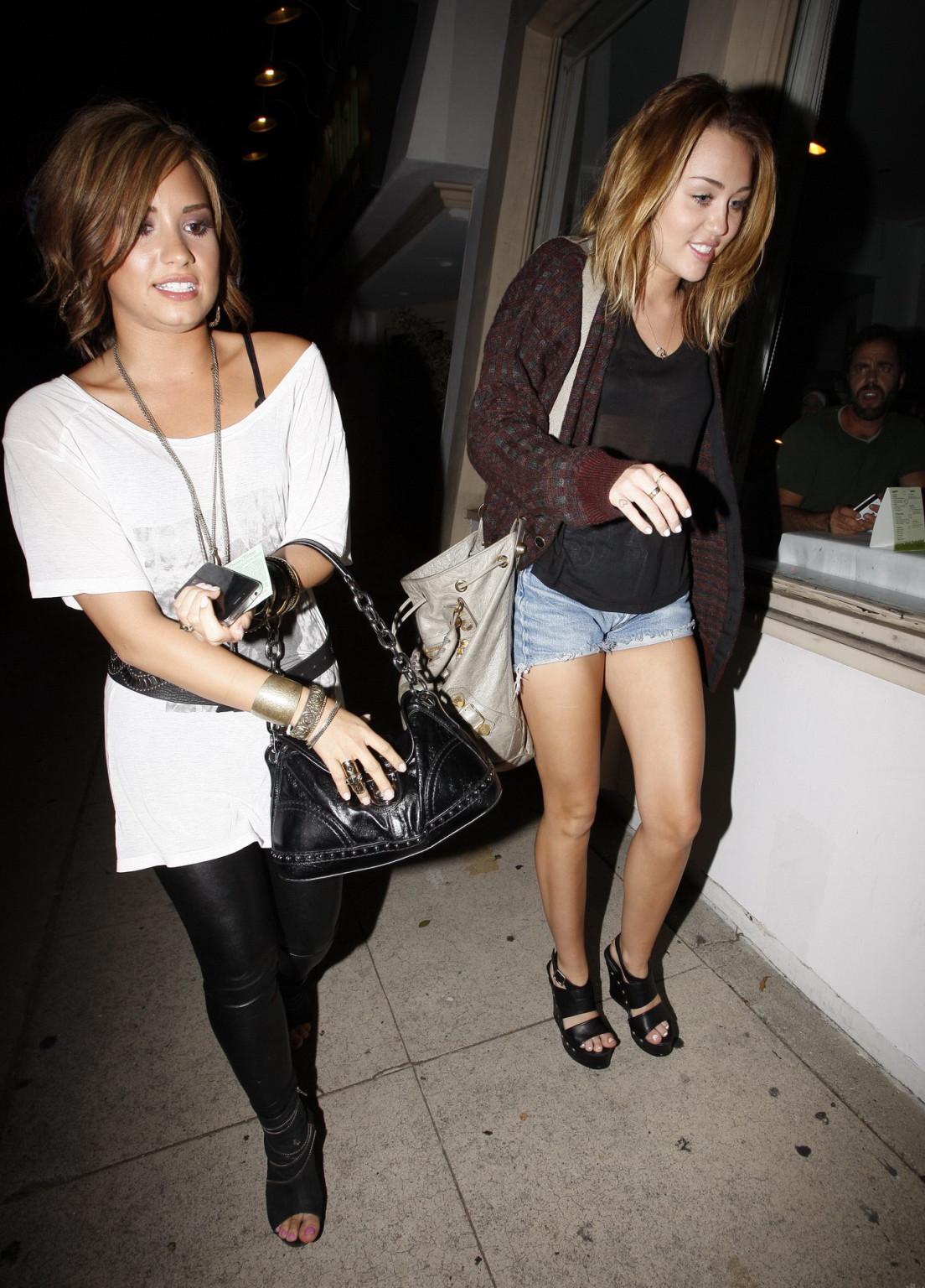 Miley Cyrusがデニムショーツに黒のブラジャーをつけて、シースルートップスを着ている。
 #75332918
