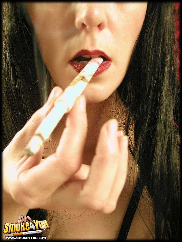 Zorra en minivestido negro se pinta los labios con el cigarrillo
 #76571813
