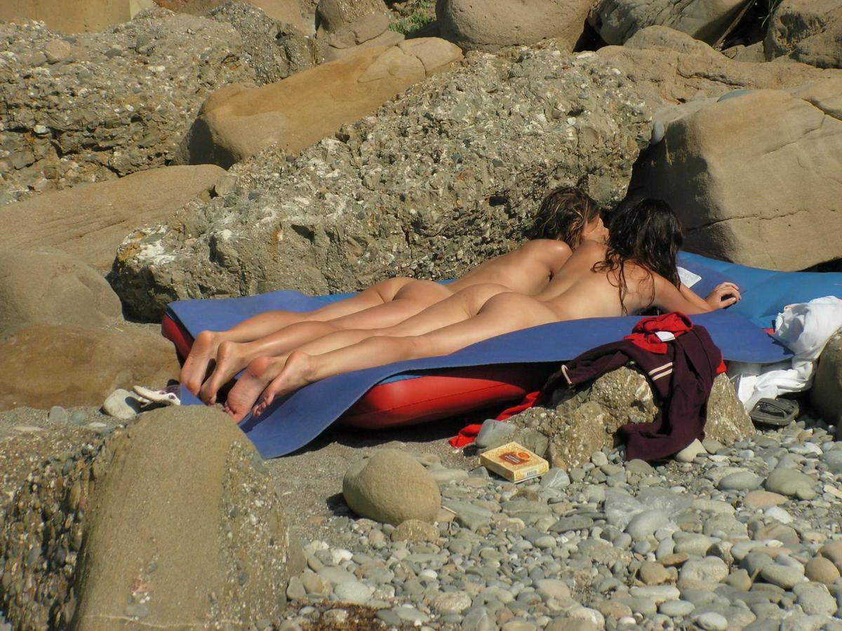 Una ragazza dai capelli lunghi si sdraia nuda in spiaggia
 #72249944