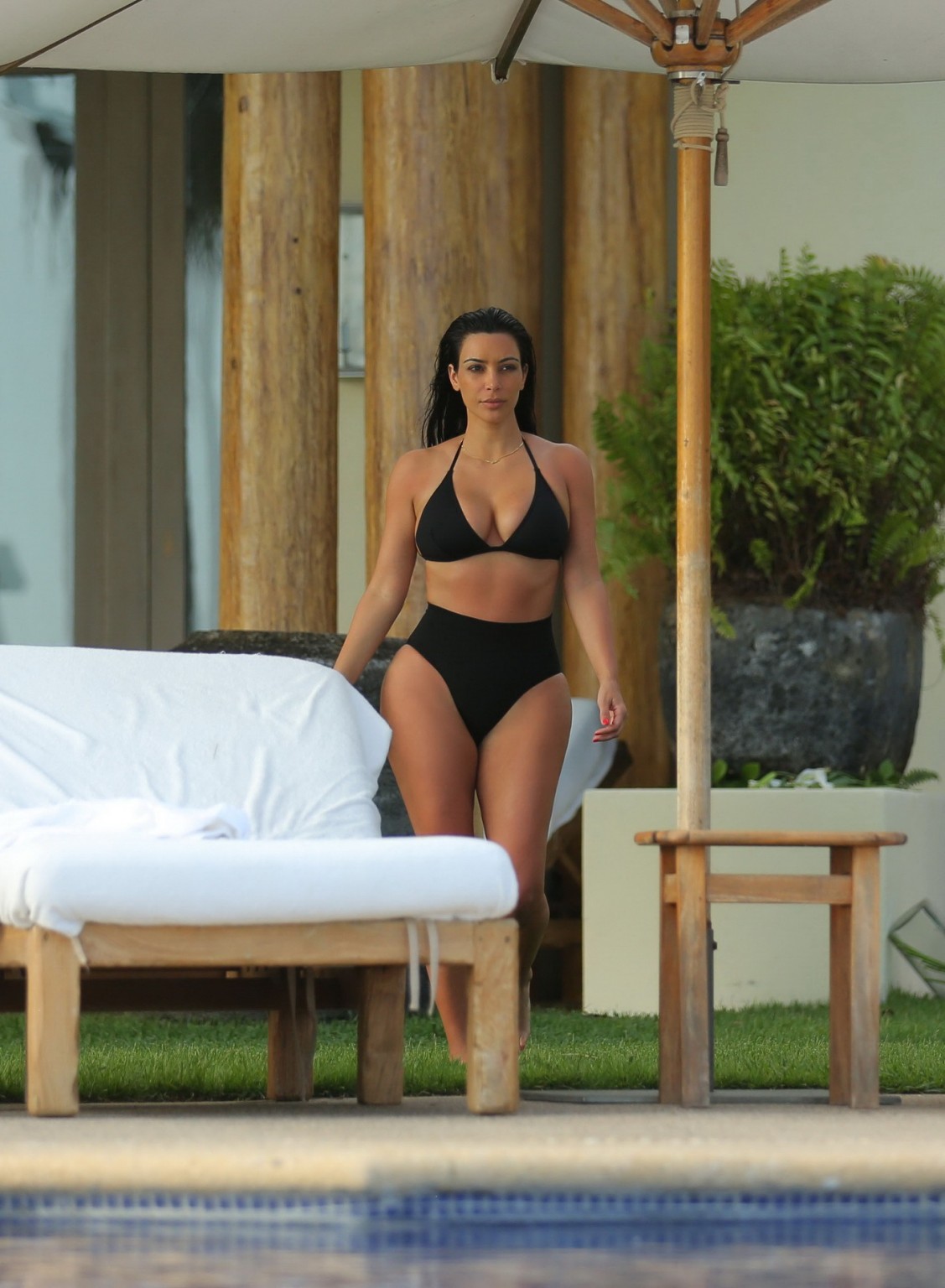 Kim Kardashian shows off her curvy body in a skimpy black bikini at the pool in 