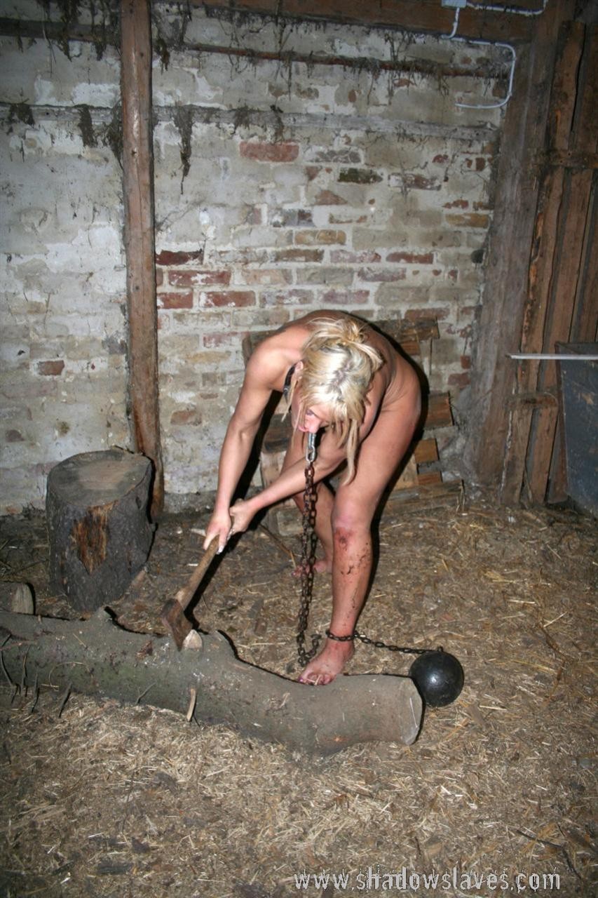 鎖に繋がれた金髪の奴隷少女が薪割りをさせられる
 #72210931