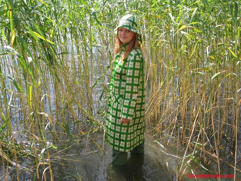 Girl in green rainwear and fishermans rubber boots #73287769