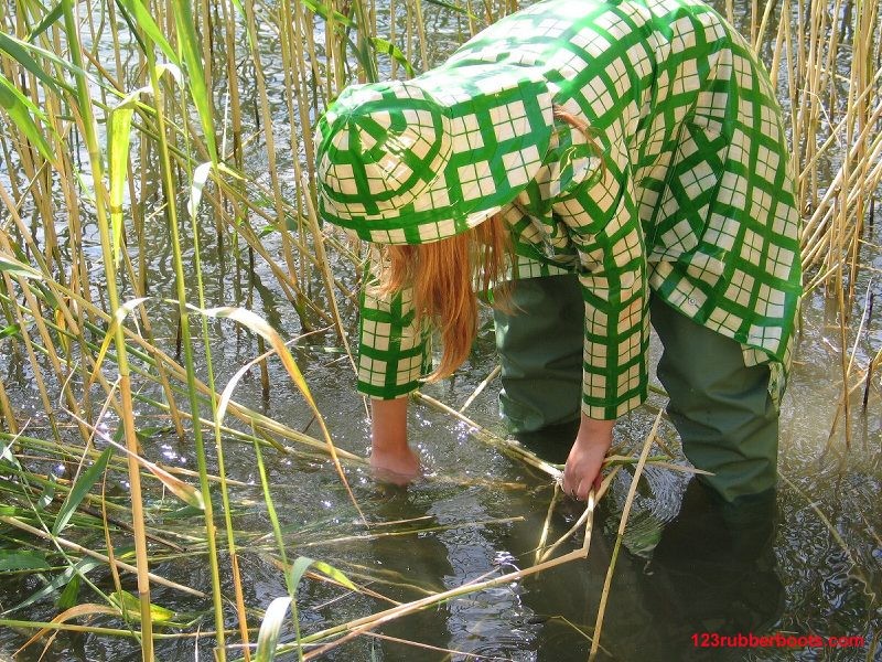 Ragazza in abiti verdi da pioggia e stivali di gomma da pescatore
 #73287780