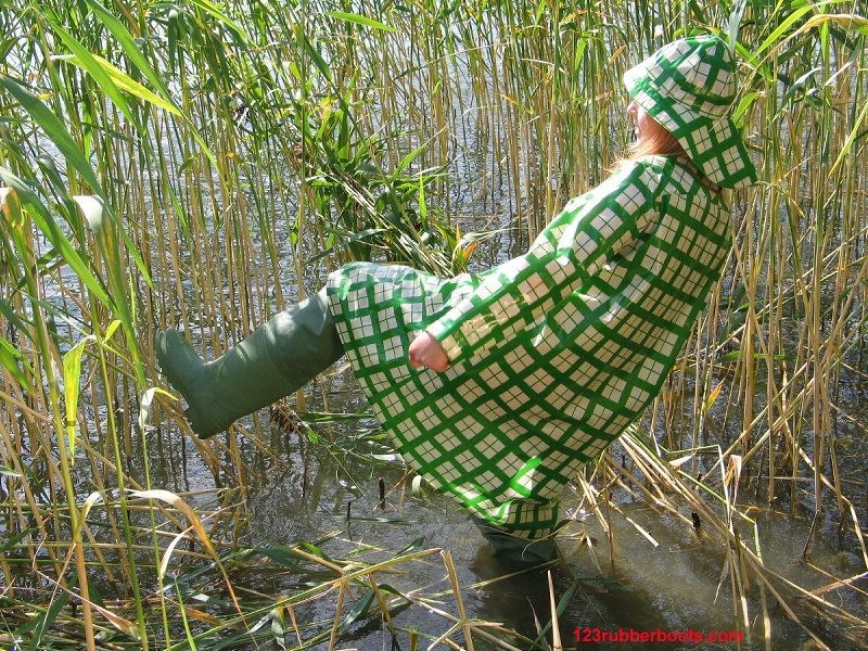 Ragazza in abiti verdi da pioggia e stivali di gomma da pescatore
 #73287786