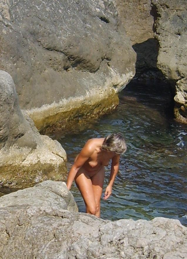 Una diosa desnuda de pechos firmes posa en una playa nudista
 #72254032