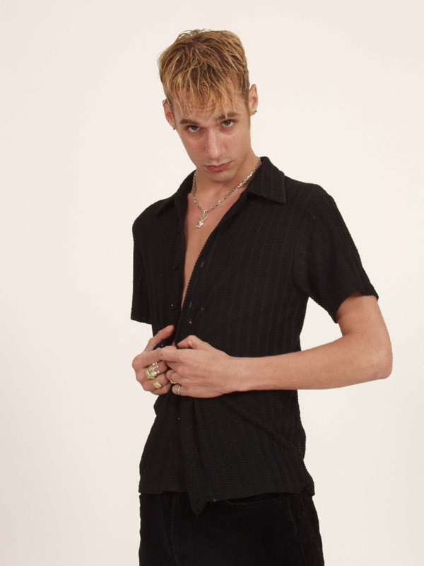 Un jovencito rubio se desabrocha la camisa y muestra algo de piel
 #77003122