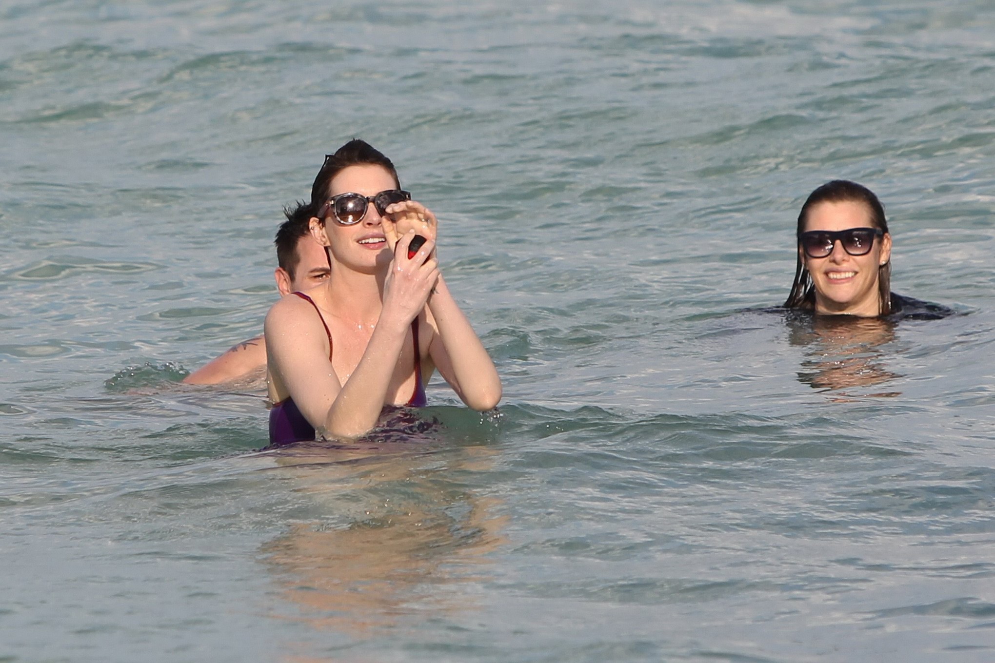 Anne hathaway con traje de baño transparente morado mojado y pantalones cortos en la playa en
 #75200954