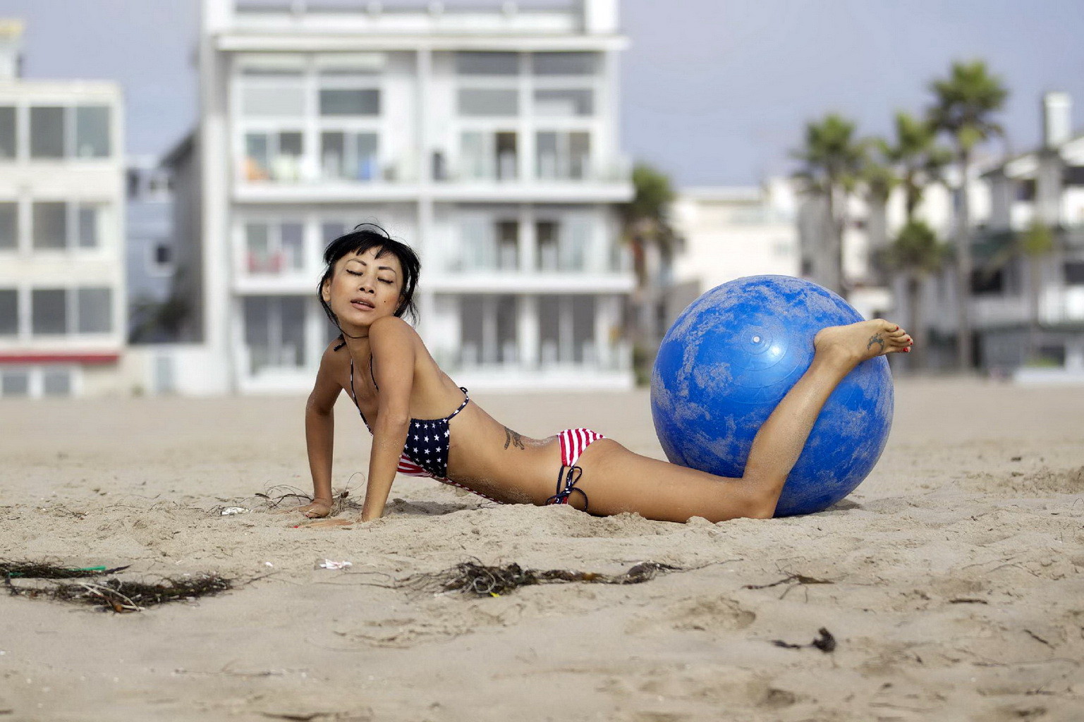 Bai ling con un monokini de rayas estrelladas montando una pelota de pilates en una playa de la
 #75251068