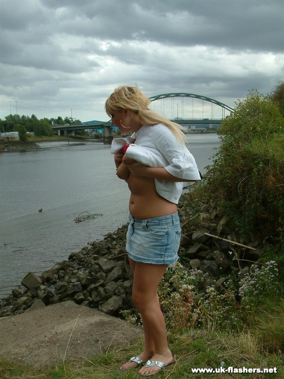 Jeune blonde aux gros seins qui s'exhibe et joue avec sa chatte en public près d'un pont.
 #78889349