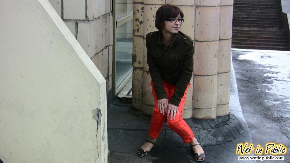 Chica de pelo corto en gafas se mea en sus pantalones rojos bajo las miradas de la gente
 #73245354