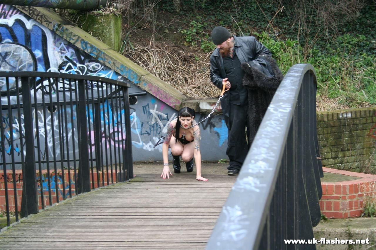 Une jeune femme gothique, épine dans le pied, marche en laisse et s'exhibe nue devant un public. 
 #76544687