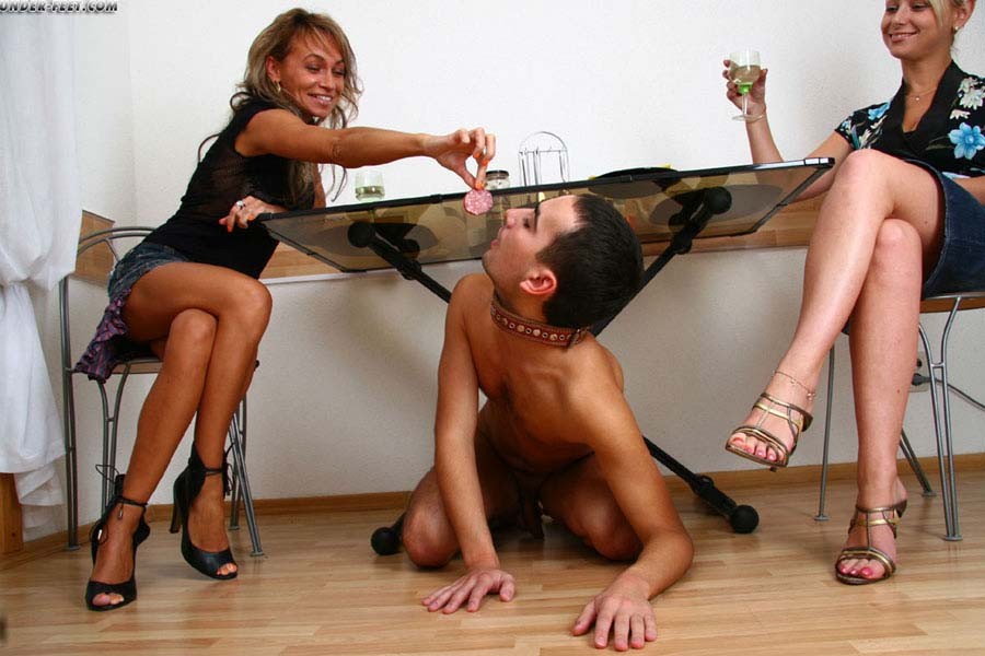 女友達がシャンパンを飲みながら、テーブルの下に潜り込んだ奴隷に餌を与えています。
 #71068737
