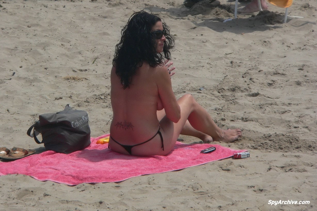 Spying on a topless milf spreading on the beach