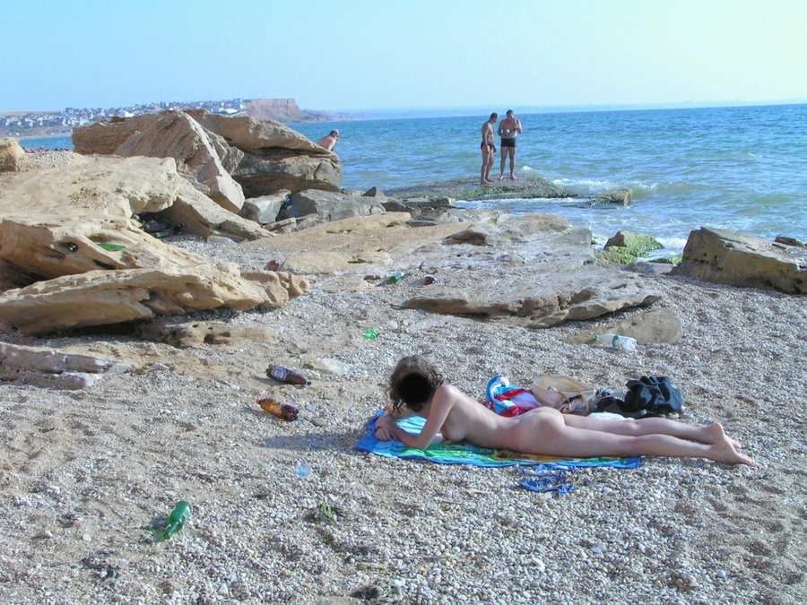 Nudista bionda tira calci all'acqua in una spiaggia nudista
 #72254242