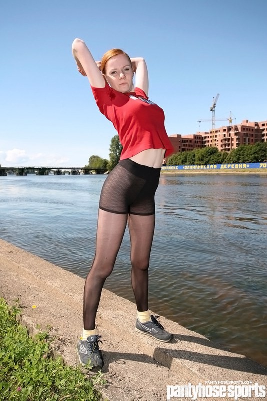 Nimfa dai capelli rossi in collant facendo aerobica in riva al fiume
 #78651271