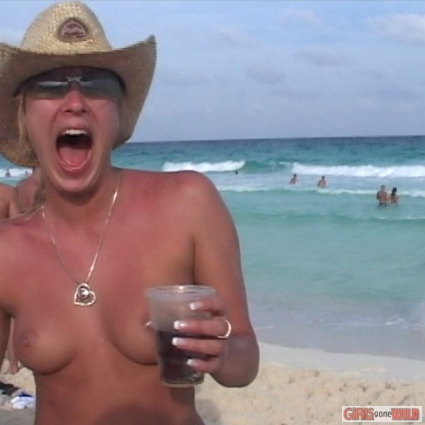 Nena joven en topless en la playa bebiendo una cerveza
 #72321616