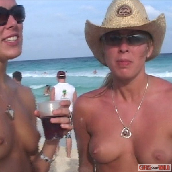 Jeune femme aux seins nus sur la plage buvant une bière
 #72321638