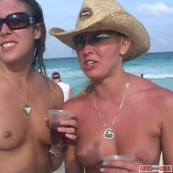 Nena joven en topless en la playa bebiendo una cerveza
 #72321646