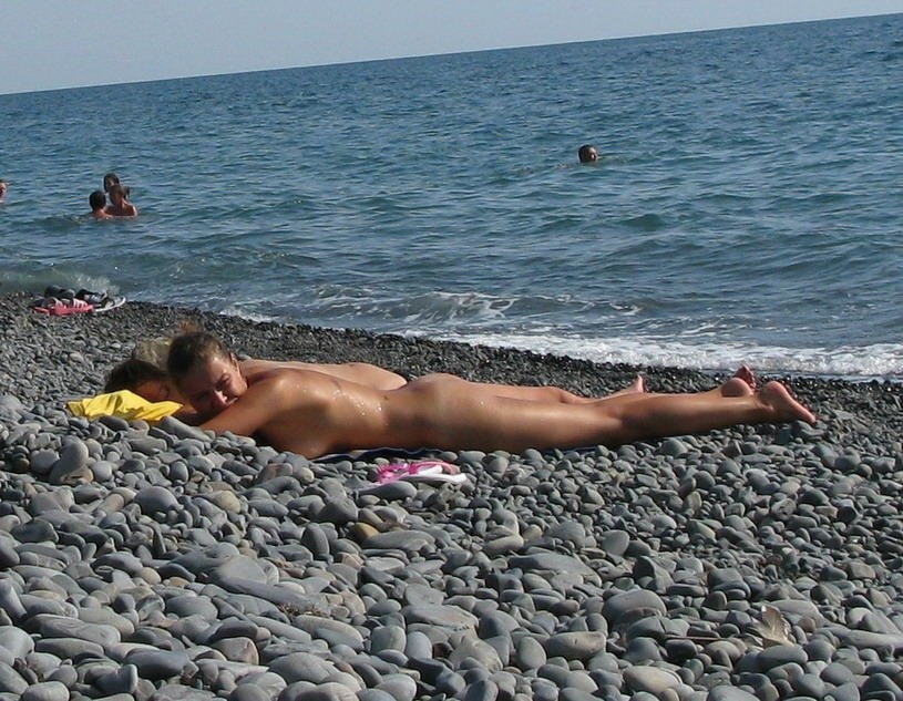 Jeune mince aux seins volumineux, nue sur une plage nudiste.
 #72256299