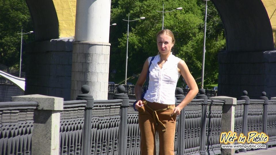 Una chica desesperada orina a través de sus pantalones de terciopelo en un terraplén del río de la ciudad
 #73238613