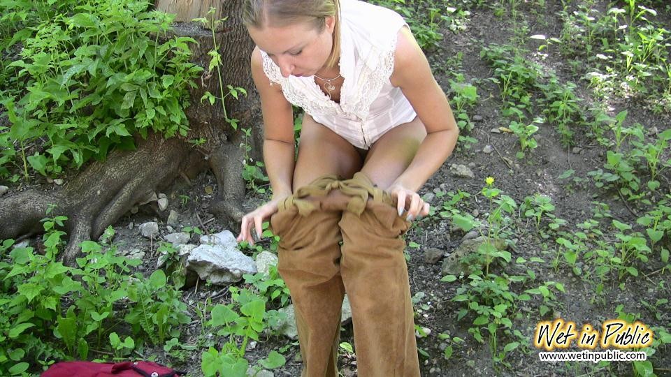 Una chica desesperada orina a través de sus pantalones de terciopelo en un terraplén del río de la ciudad
 #73238648