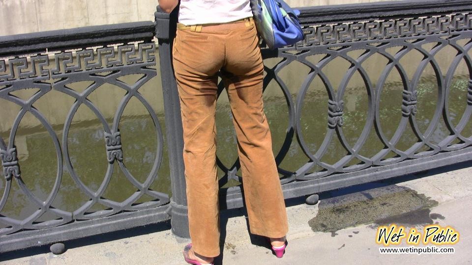 Una chica desesperada orina a través de sus pantalones de terciopelo en un terraplén del río de la ciudad
 #73238652
