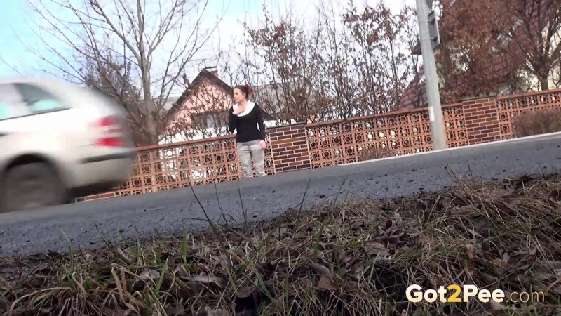 Brunette girl needs to pee while walking by a road #67480740
