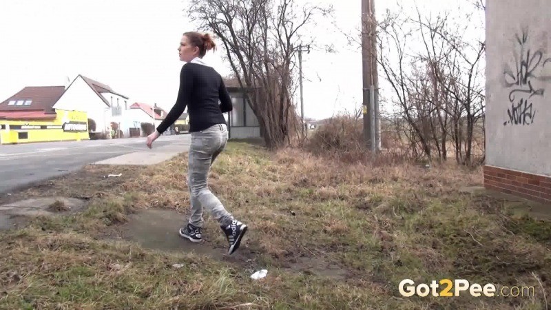 Brunette girl needs to pee while walking by a road #67480824